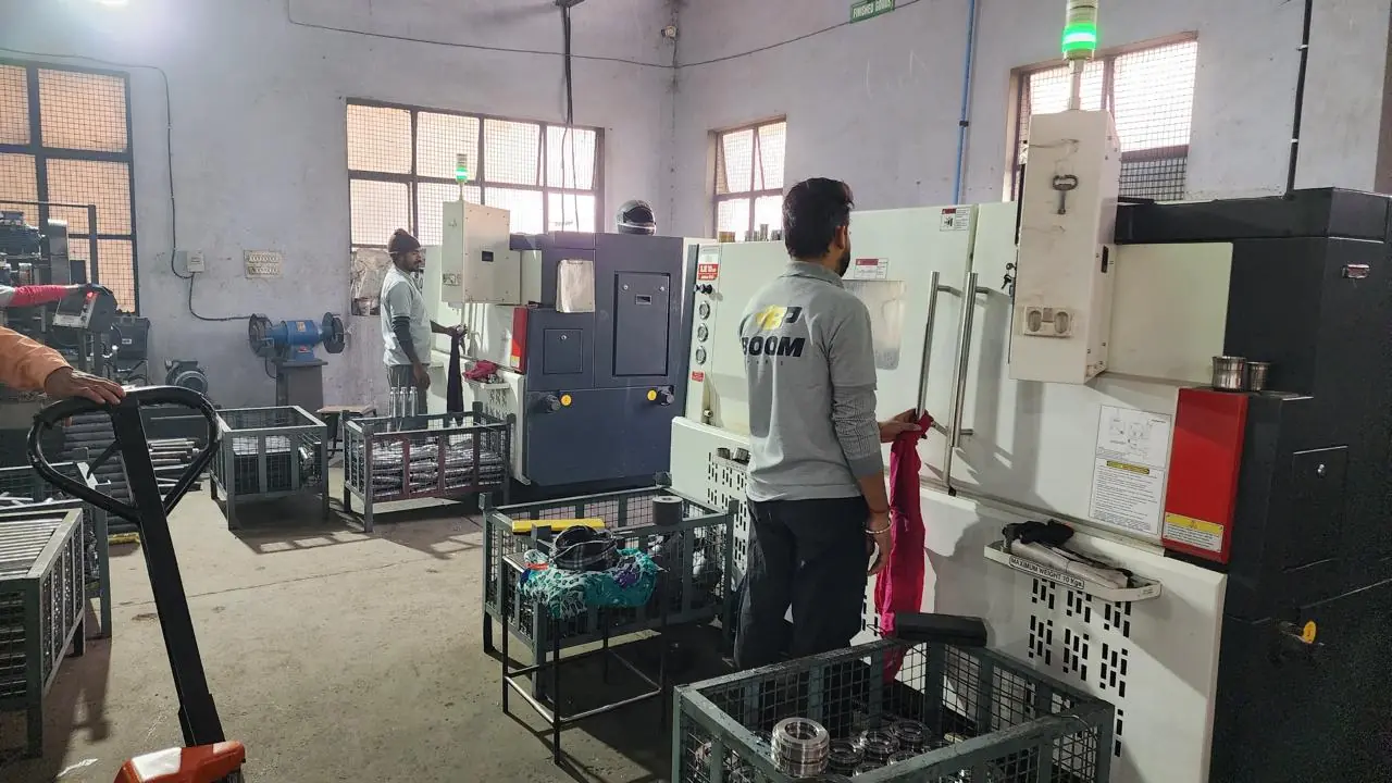 BOOM Parts operator working at a CNC turning centre with bins of machined components