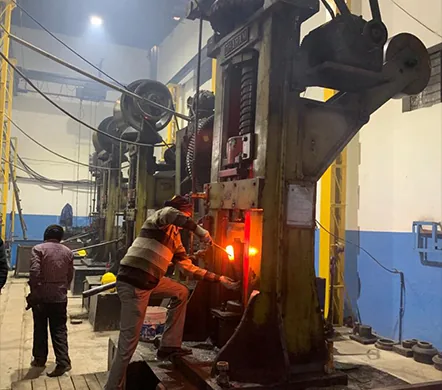 Operator working a hot part on a forging press at the BOOM Parts factory